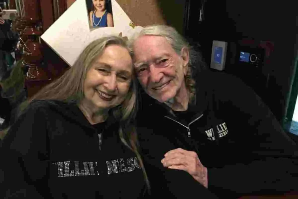 Willie Nelson and Bobbie Nelson smiling together in a casual indoor photo, seated closely and dressed in black.