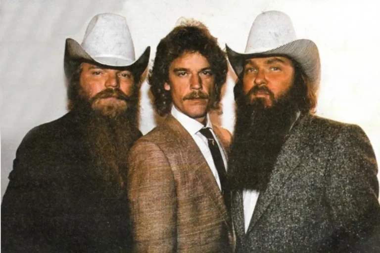 ZZ Top band members standing shoulder to shoulder in color, wearing suits and white cowboy hats.