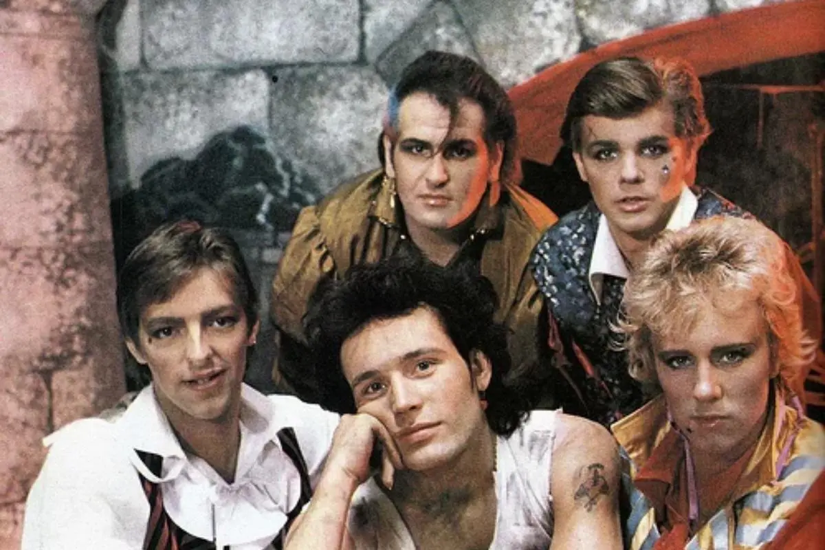 Adam and the Ants posing together in colorful, theatrical New Romantic costumes.