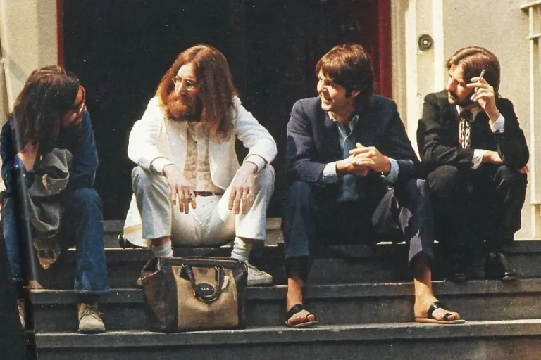 The Beatles sitting on outdoor steps in the late 1960s.