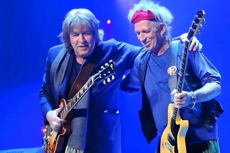 Bill Wyman and Keith Richards, stand together onstage under blue lighting.