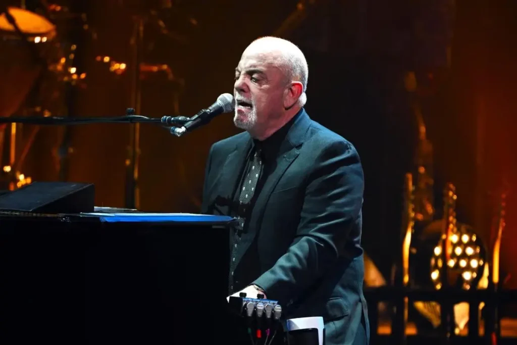 Billy Joel sits at a grand piano during a live performance.