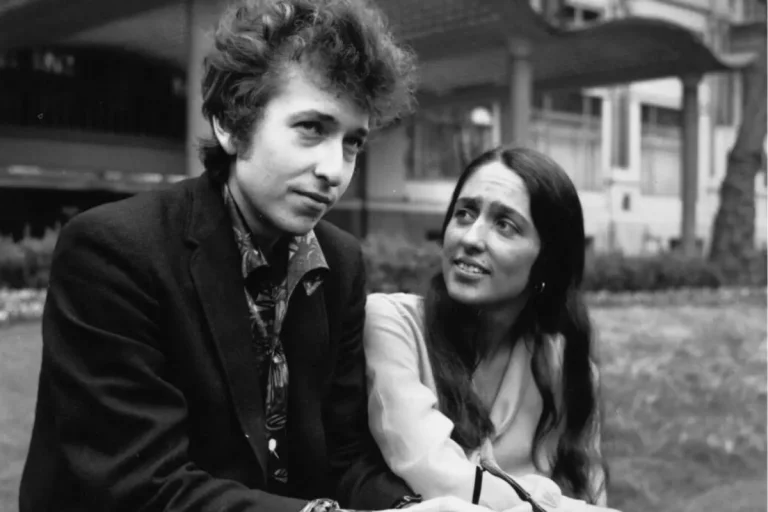 Bob Dylan and Joan Baez sit outdoors in a candid moment.