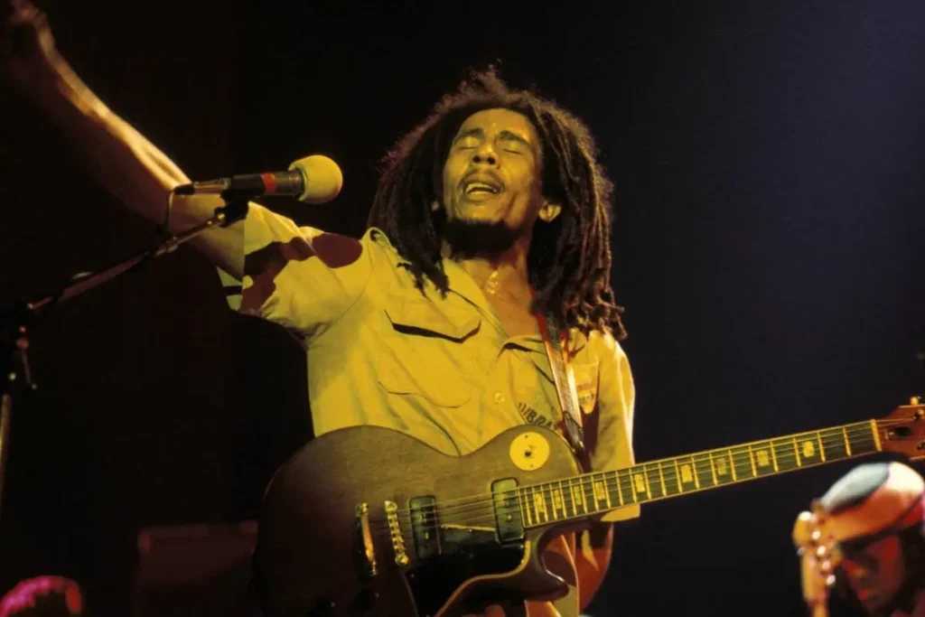 Bob Marley performs passionately onstage with his guitar.