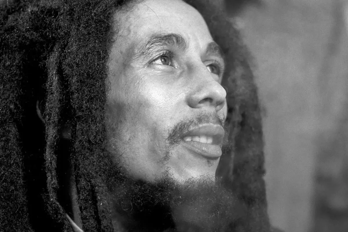 Bob Marley looking upward with a soft, reflective expression, his dreadlocks framing his face.
