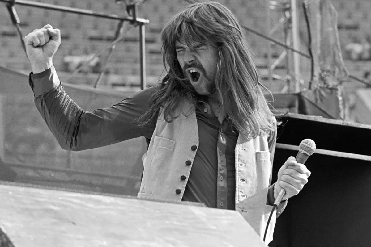Bob Seger singing passionately on stage, fist raised while gripping a microphone.