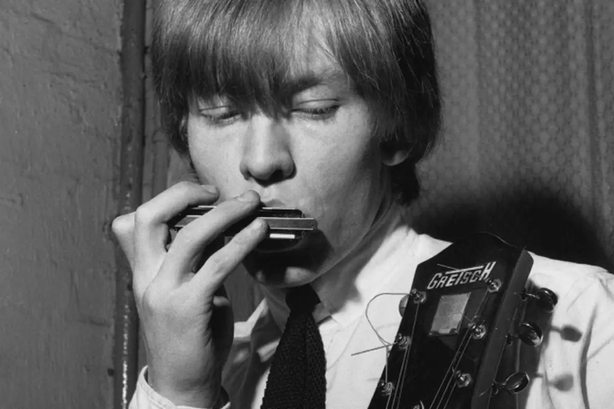 Brian Jones playing a harmonica.