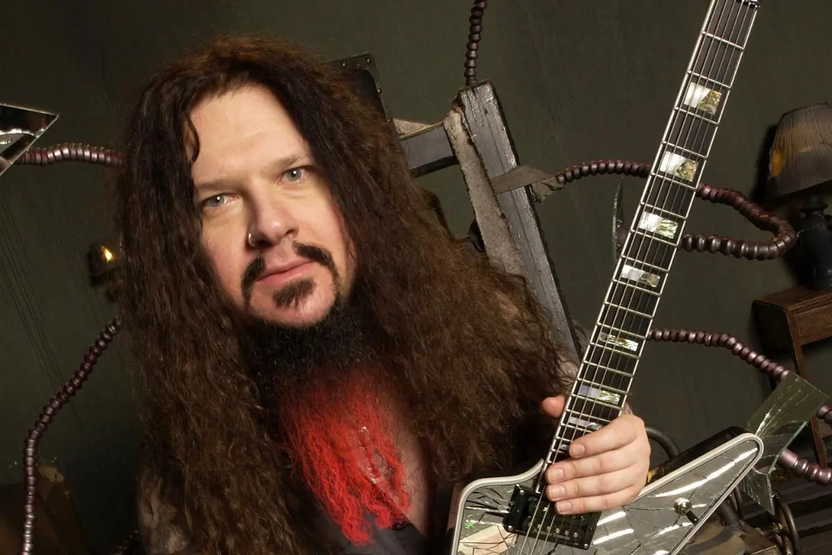 Dimebag Darrell holding a mirrored electric guitar.