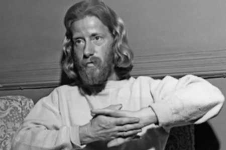 Black-and-white portrait of Eden Ahbez seated indoors with long hair and beard.