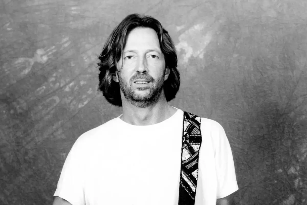 Eric Clapton standing against a textured studio backdrop.