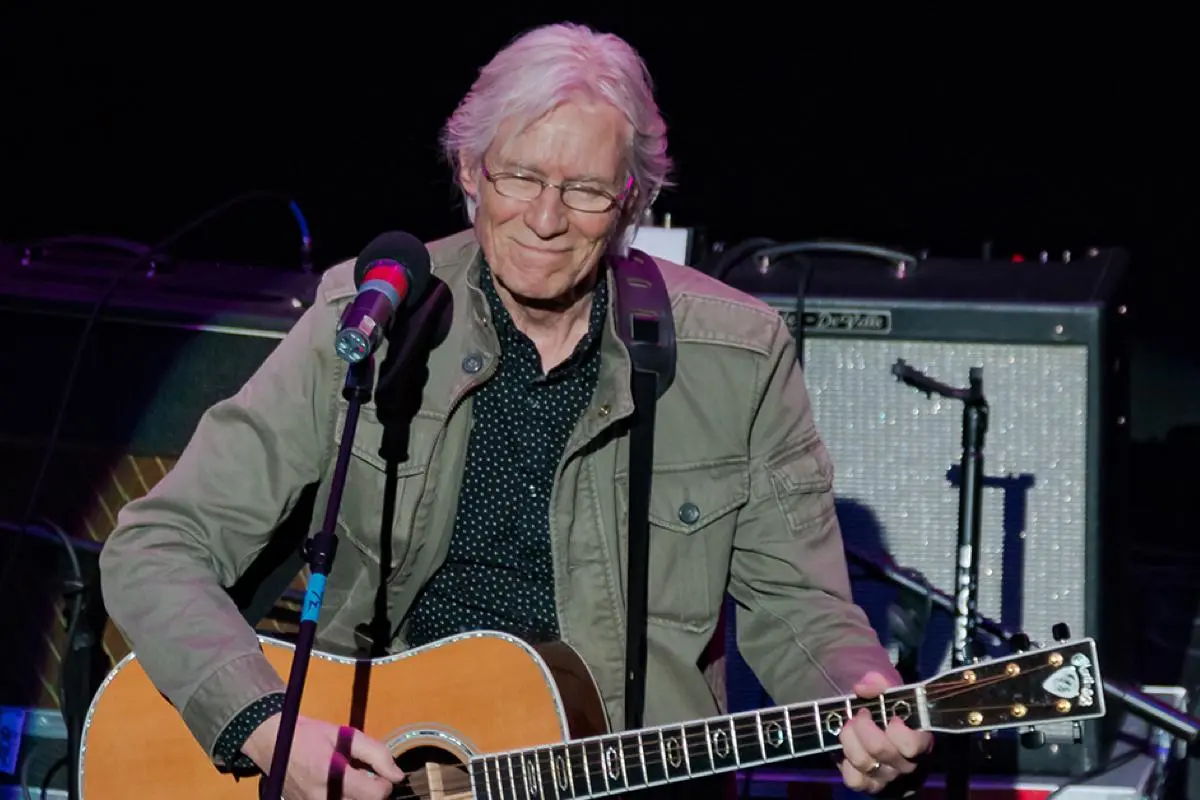 Hilton Valentine performing onstage with an acoustic guitar.