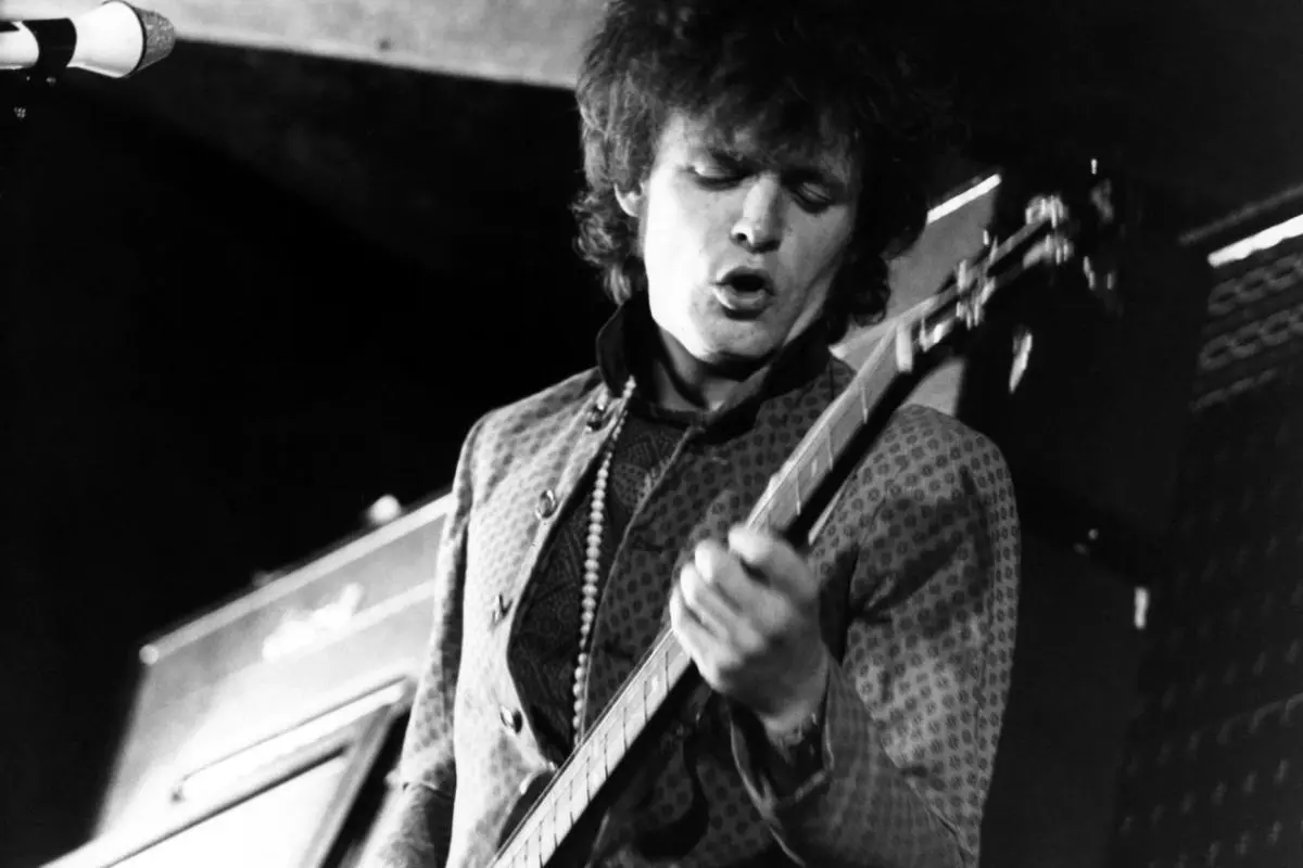 Jack Bruce performs intensely onstage, captured in black and white mid-song.