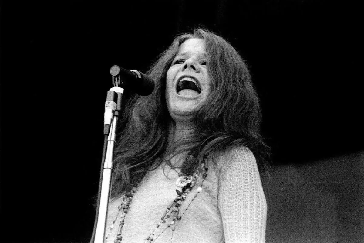 Janis Joplin singing passionately into a microphone on stage.
