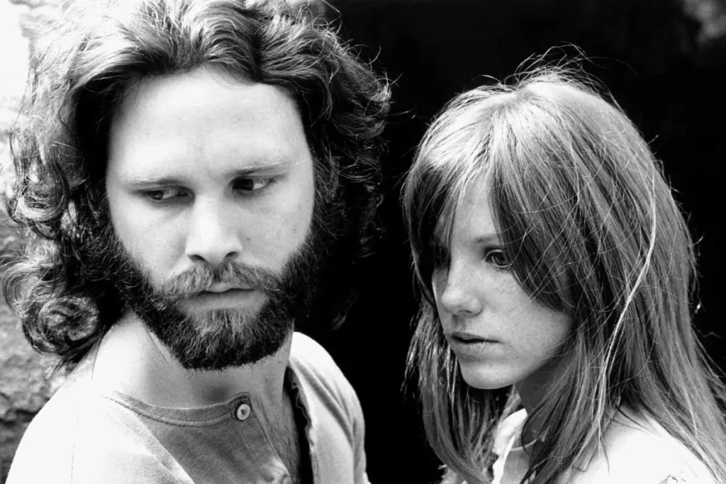 Jim Morrison and Pamela Courson standing together both looking serious