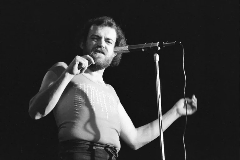 Joe Cocker performing live at a microphone in a black-and-white concert photo.