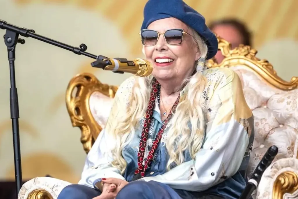 From Baritone Ukulele to “Weird Chords”: Joni Mitchell’s Secret Origin Story Joni Mitchell sits on an ornate gold and cream chair while performing.
