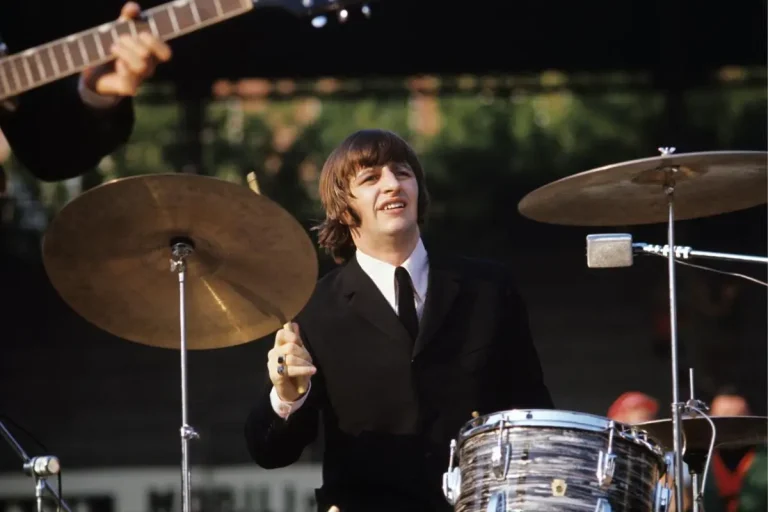 Ringo Starr performing live on stage behind a drum kit.