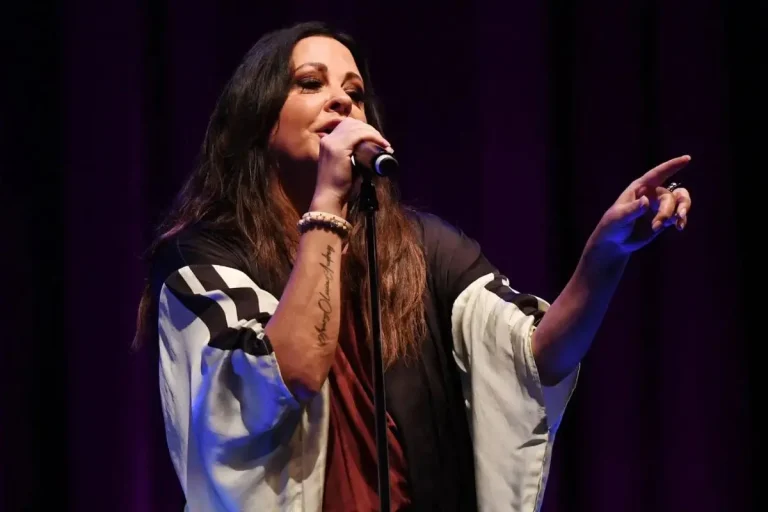 Sara Evans performs onstage, holding a microphone with one hand.