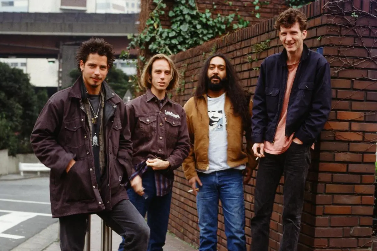 Soundgarden band members standing together outdoors near a brick wall.
