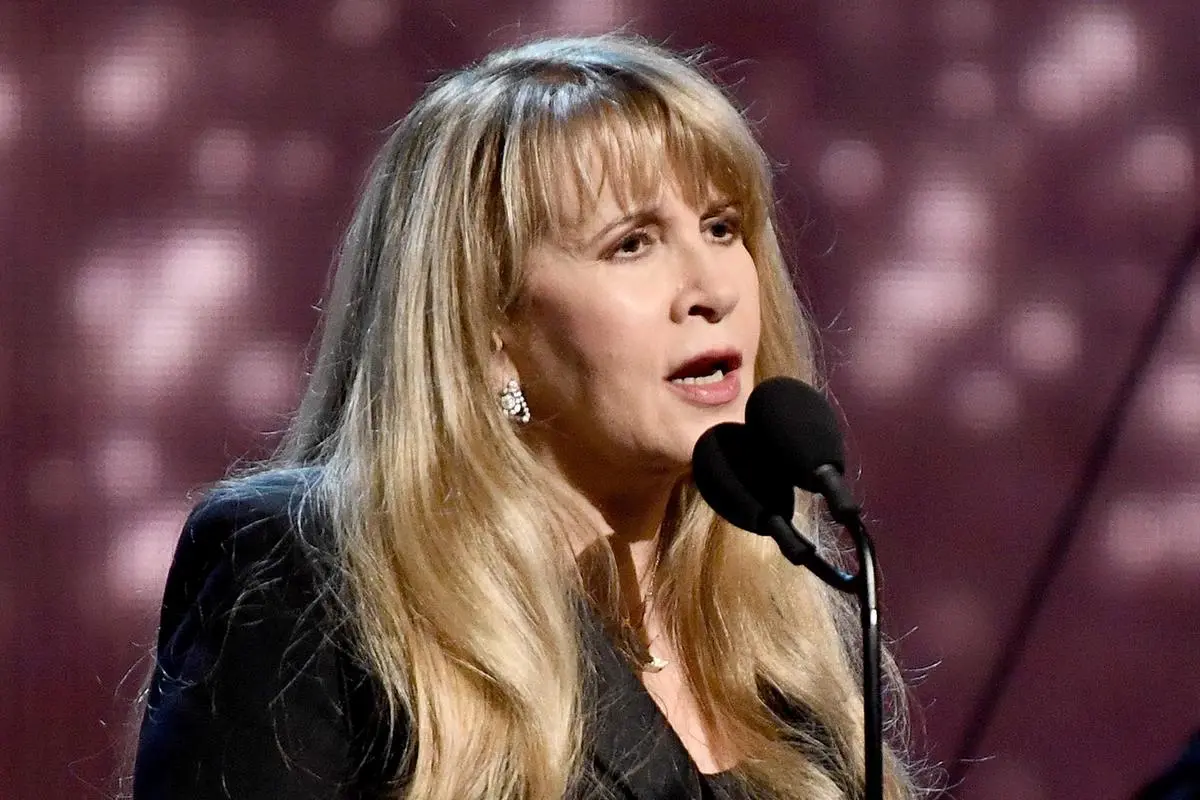 Stevie Nicks performing on stage, singing into a microphone.