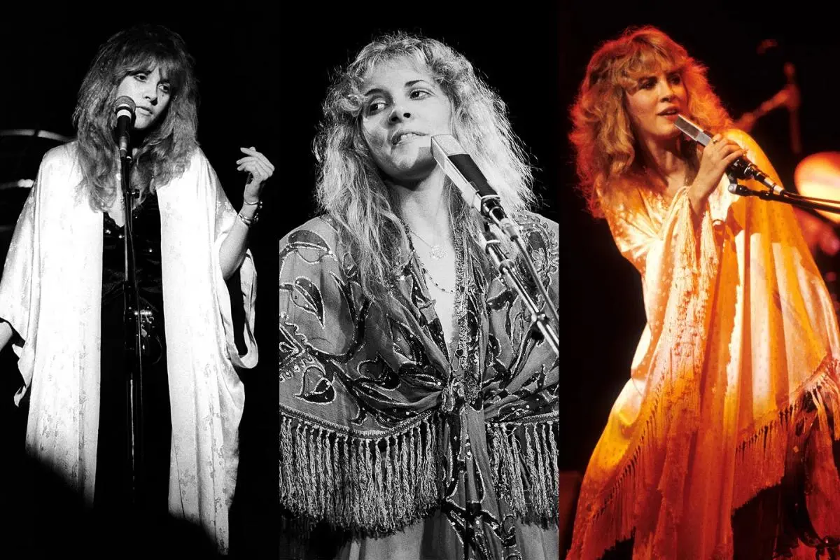 Stevie Nicks performs onstage in a flowing shawl, holding a microphone under soft stage lighting.