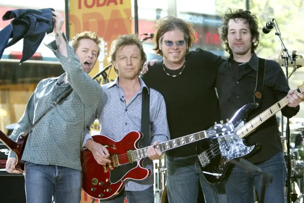 The Rembrandts pose together on an outdoor stage.