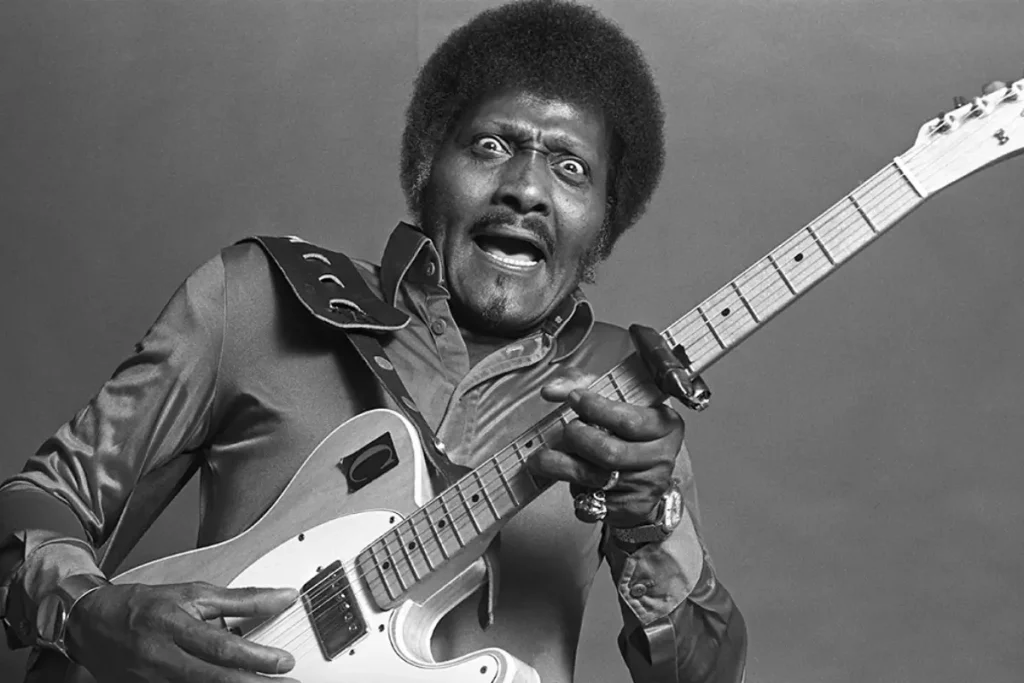 A blues guitarist grips a Fender Telecaster mid-expression, his wide-eyed intensity capturing the raw, electrifying force that defined his signature playing style.