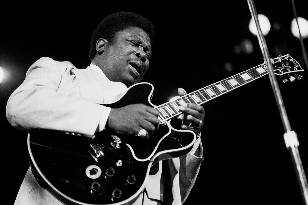 B.B. King playing guitar on stage, eyes closed in concentration, highlighting the emotional intensity and skill of his blues musicianship.