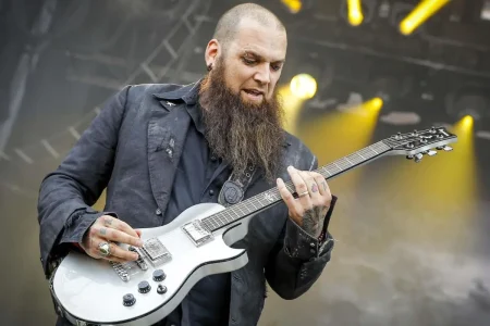 Barry Stock sings into a handheld microphone on stage.