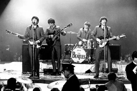 The Beatles performing live on stage in matching suits, 1960s concert.