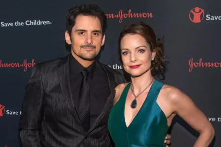 Brad Paisley and Kimberly Williams-Paisley pose together on a red carpet, both dressed formally and smiling at the camera.