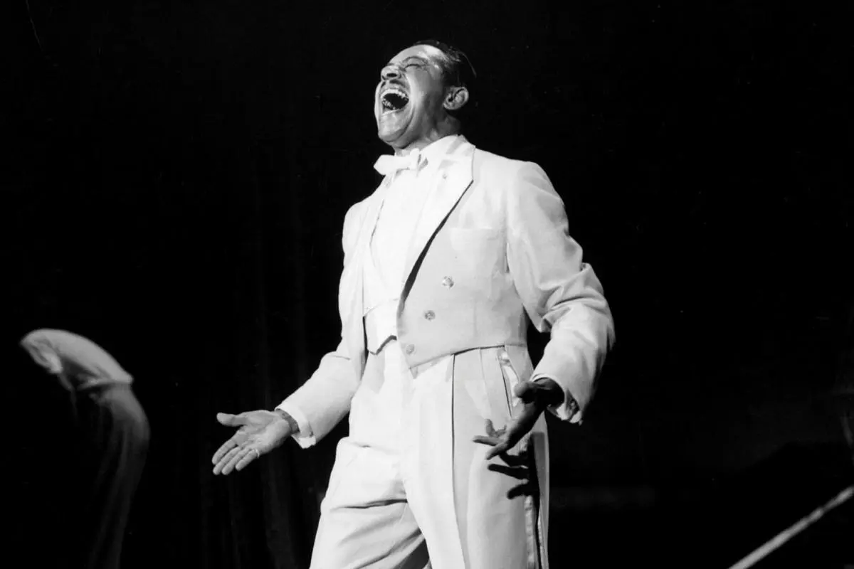 Cab Calloway head thrown back mid-song with mouth wide open, arms extended in an expressive stage pose.
