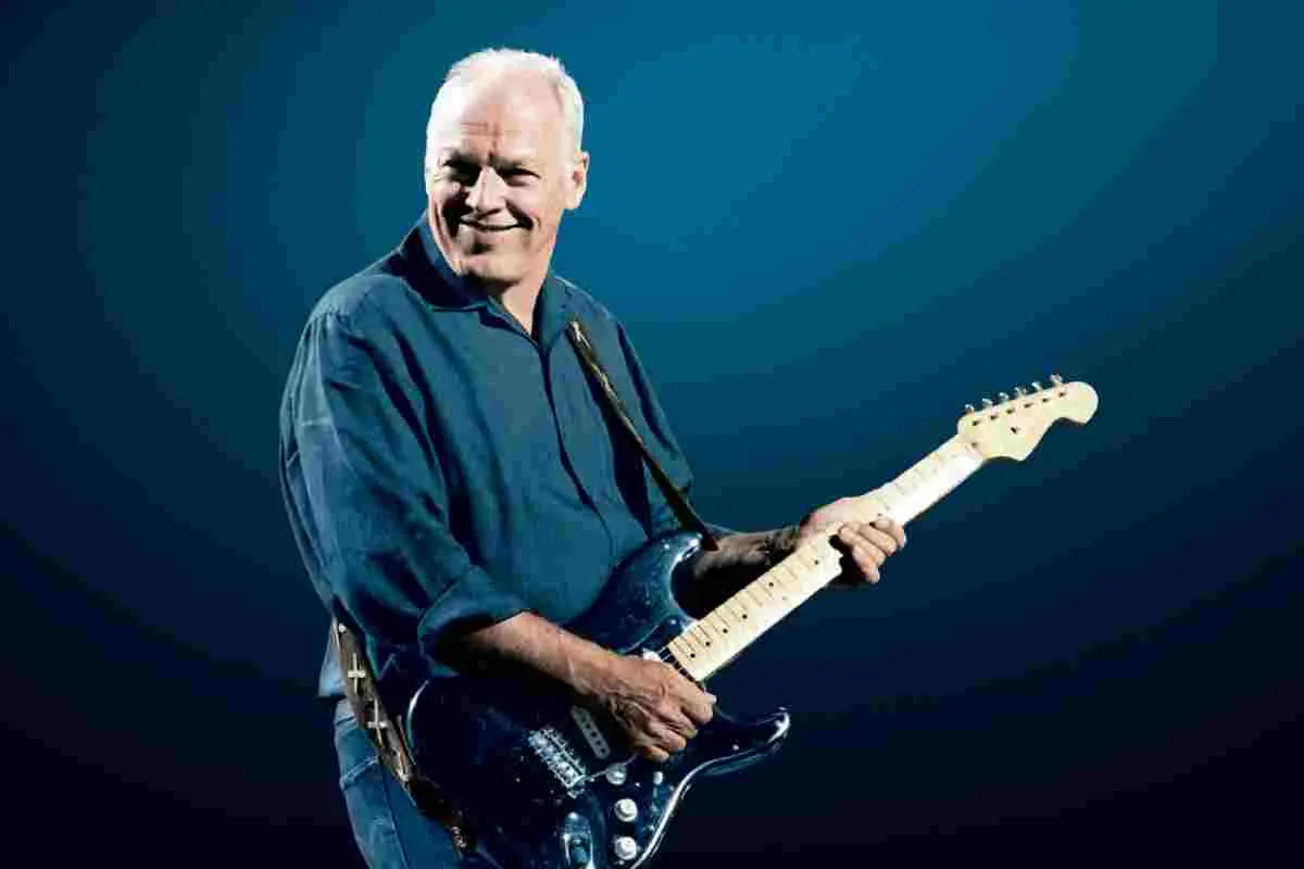 David Gilmour smiling on stage while playing electric guitar.