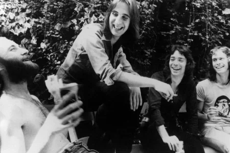 Genesis band members relaxing outdoors in a candid black-and-white group photo.