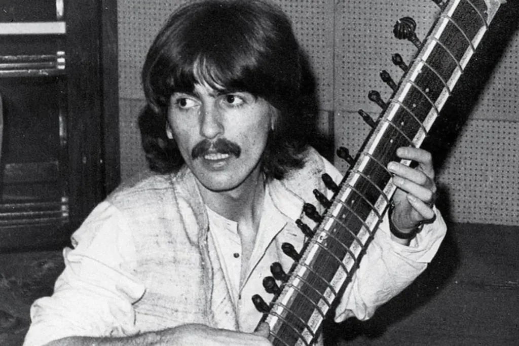 George Harrison holding a sitar during a studio session.