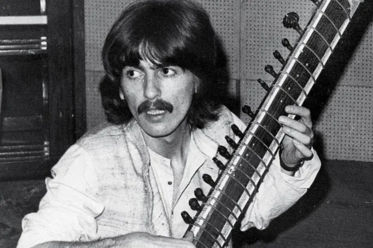 George Harrison holding a sitar during a studio session.