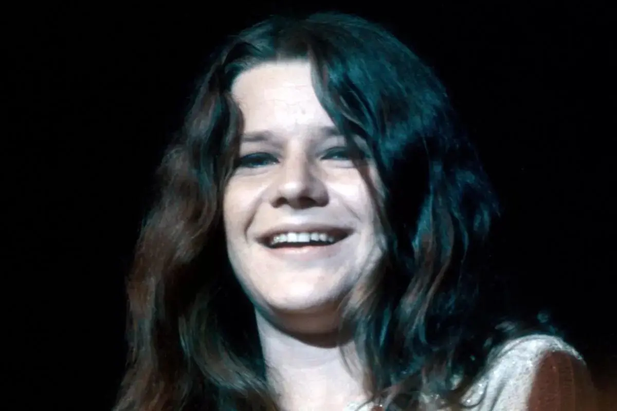 Janis Joplin expressive facial emotion, and animated movement as she sings into a microphone on stage.