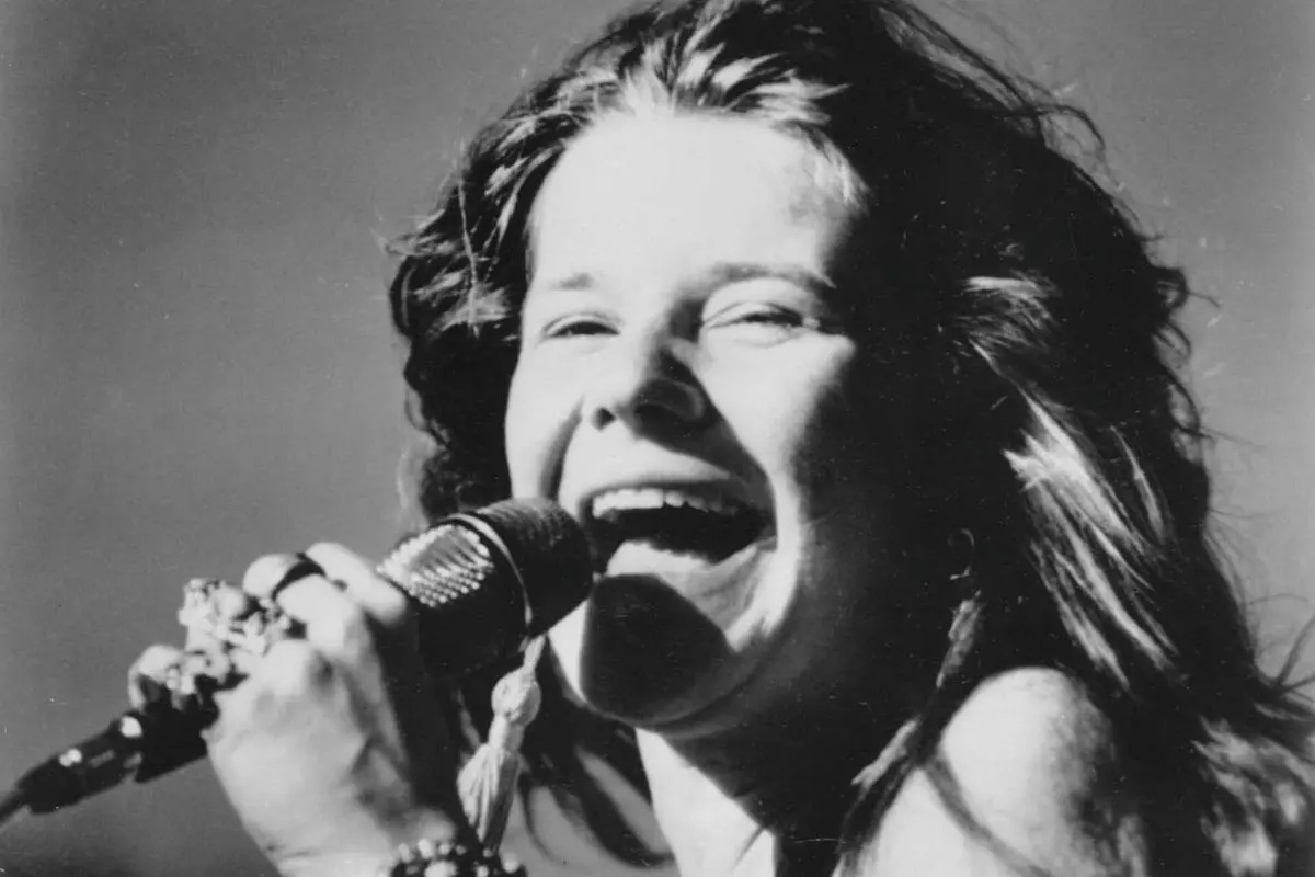 Janis Joplin captured mid-song, wearing flowing stage attire and layered jewelry, conveying high energy and emotional intensity.