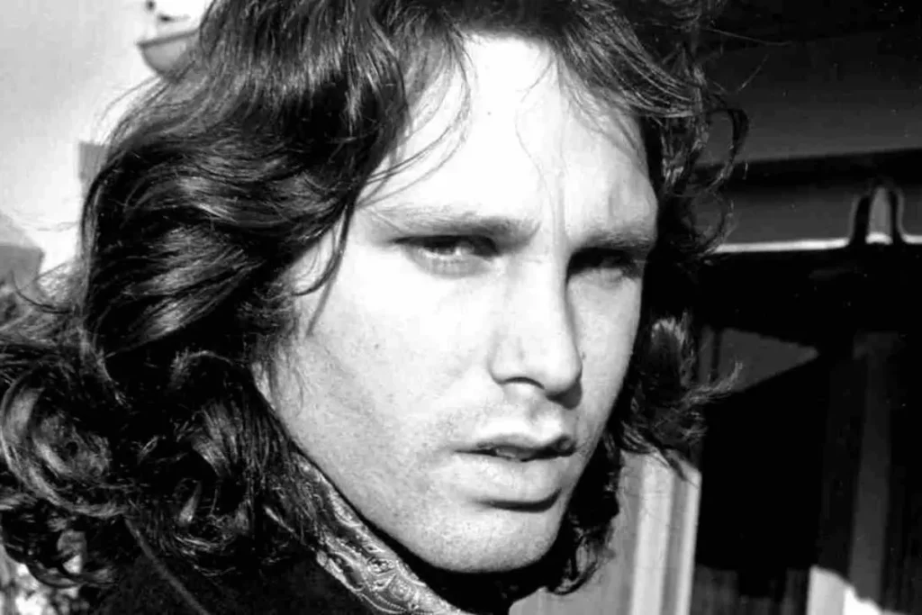 Did Oliver Stone ‘Assassinate’ Jim Morrison? The Doors Film vs. The Man, According to the Band Jim Morrison wavy hair and a serious expression, photographed outdoors with strong sunlight and shadows.