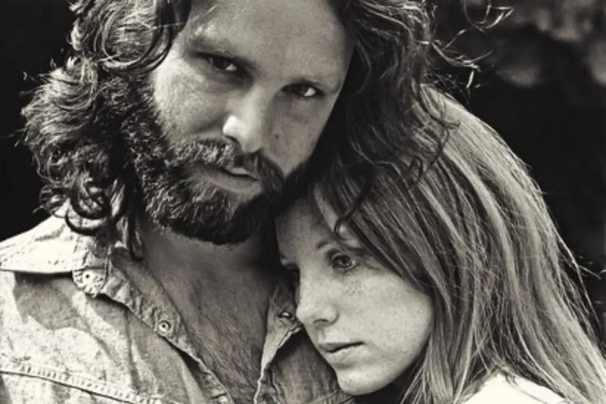 Jim Morrison and Pamela Courson stand close together outdoors, conveying an intimate and reflective moment during their relationship.