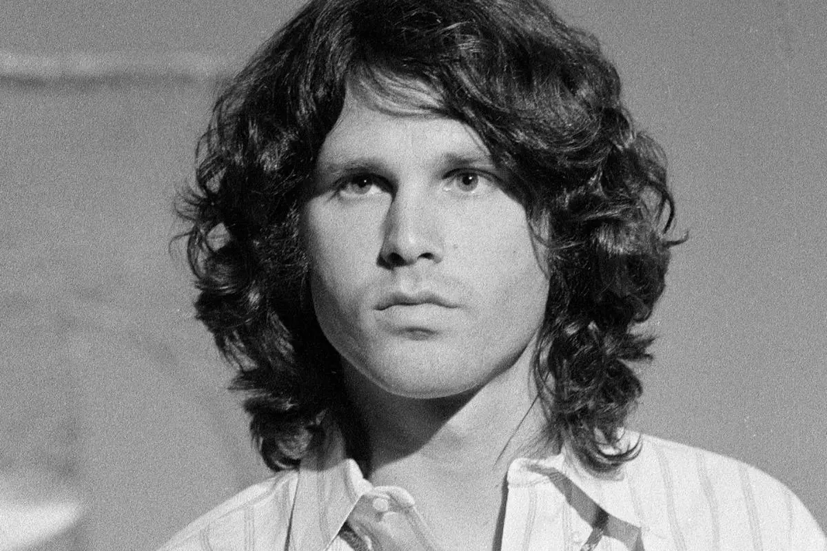 Jim Morrison wearing a light-colored shirt, looking directly ahead with a calm, intense expression.