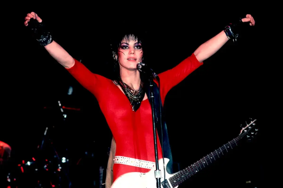 Joan Jett performing under stage lights with an electric guitar, emphasizing intensity, independence, and commanding stage presence.