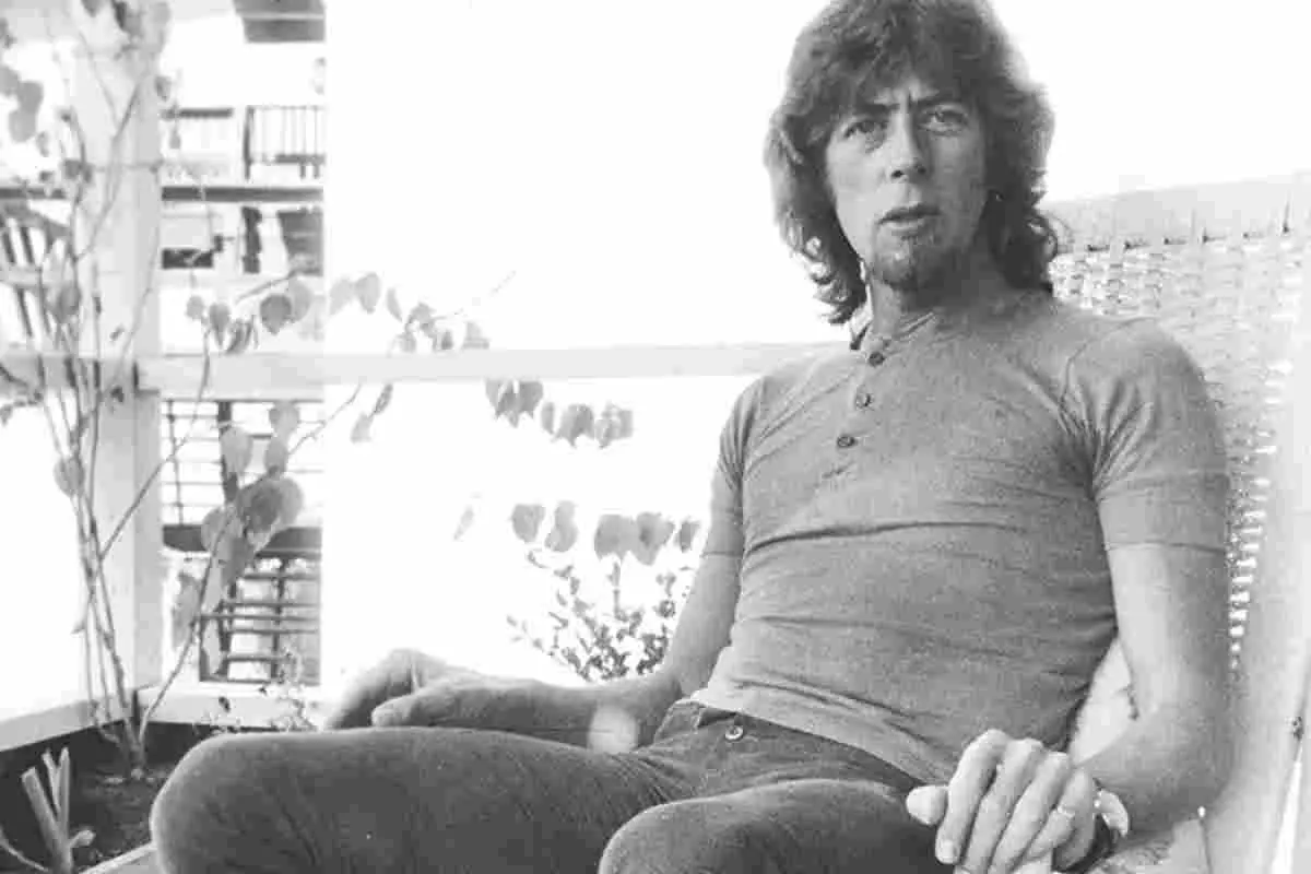 John Mayall of John Mayall & the Bluesbreakers seated outdoors in a black-and-white portrait.
