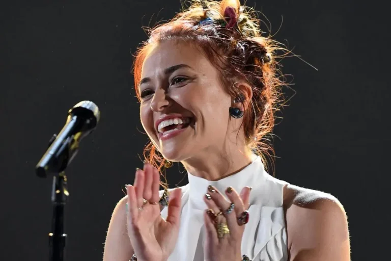 Lauren Daigle smiling and clapping on stage, hair pulled into a loose bun.