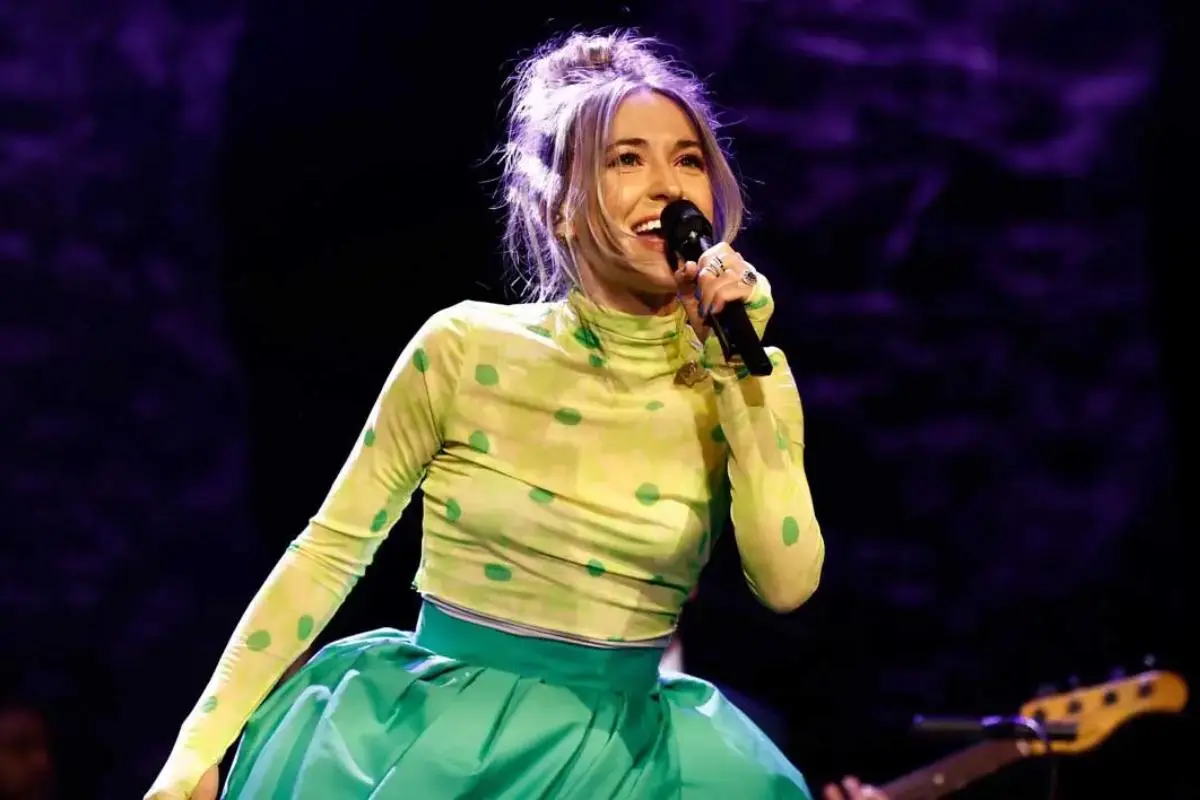 Lauren Daigle performing live in a green polka-dot top and flowing green skirt.