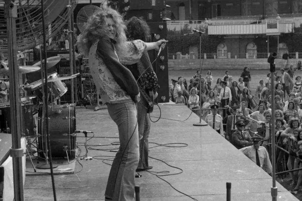 Led Zeppelin passionately into a handheld microphone on stage.