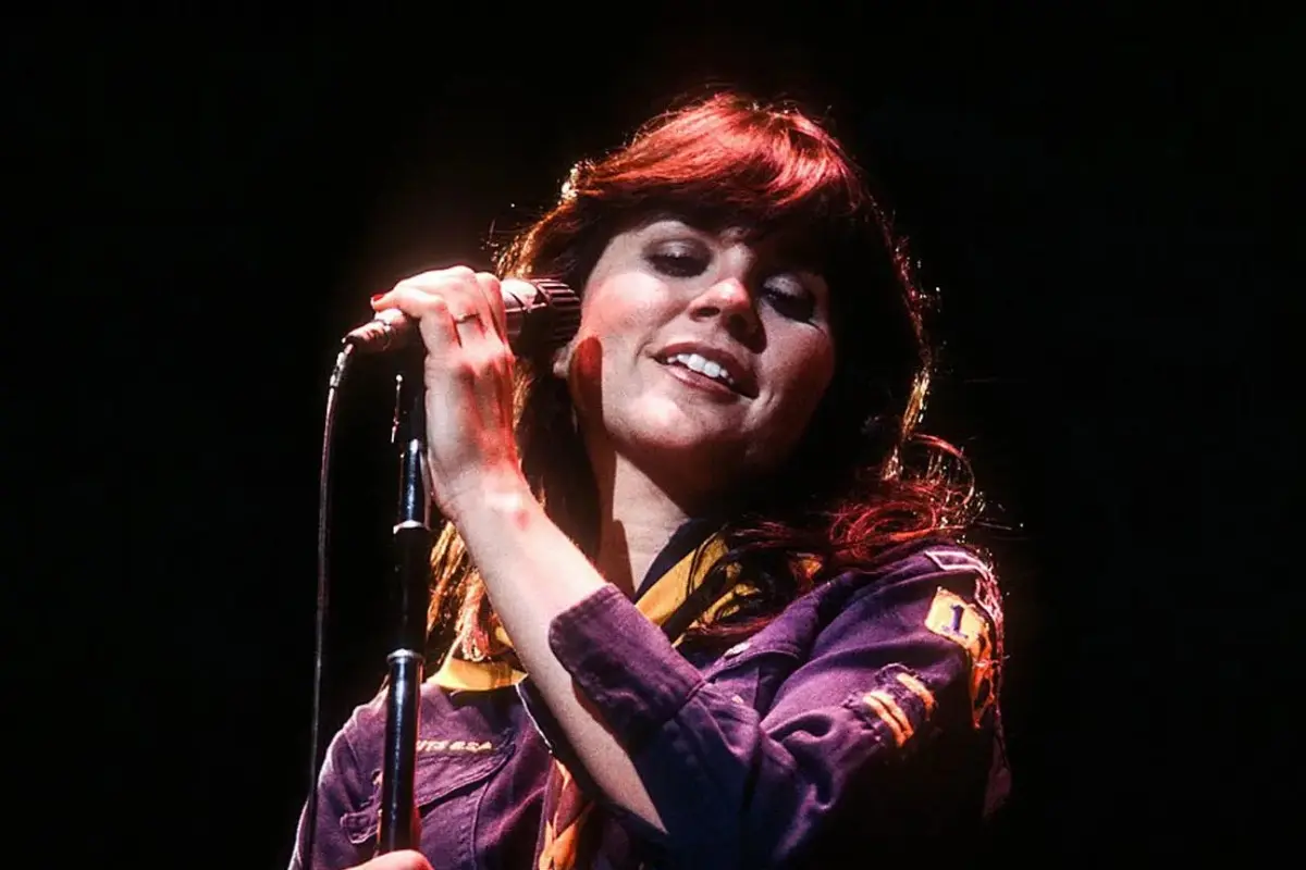 Linda Ronstadt singing into a microphone on stage, eyes closed, capturing the emotional intensity of her live performance.