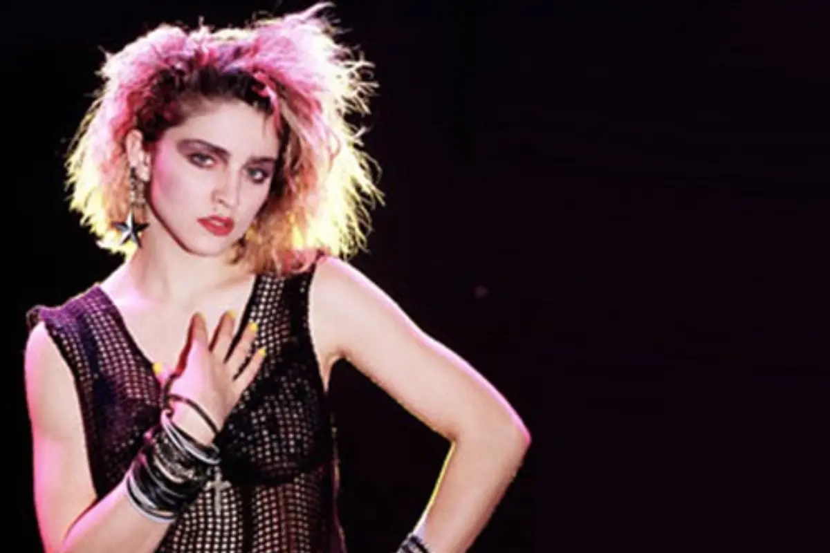 Madonna in an early 1980s studio portrait, wearing edgy fashion that reflects her emerging pop rebel persona.