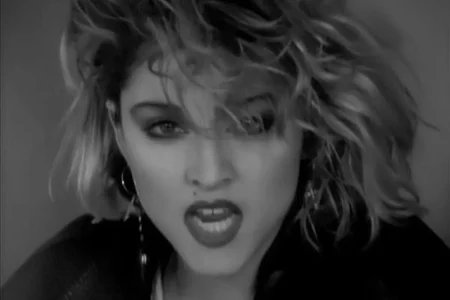 Black-and-white close-up of Madonna from a music video era, capturing her bold expression and signature 1980s pop icon style.