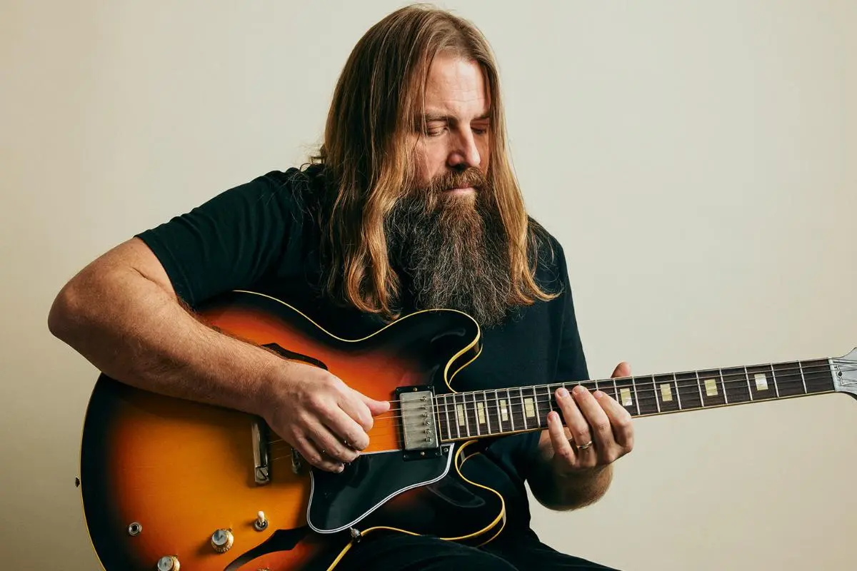 Mark Morton playing a semi-hollow electric guitar in a studio setting, focused on the fretboard.
